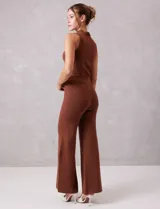 Pantalón wide leg color marrón, de tiro alto, confeccionado en tejido lurex con brillo. Modelo palazzo con pretina ancha elastizada.