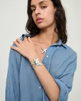 Pulsera rígida de aleación de metales bañada en plata con diseño en forma de estrella.