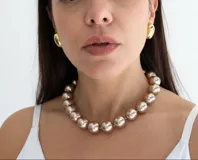 Collar de perlas redondas en tono rosado con acabado brillante, con cierre de mosquetón metálico.