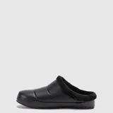 Pantuflas de diseño tipo mule, confeccionadas en material simil cuero negro con interior forrado en piel sintética negra. Presentan una suela de goma antideslizante y resistente, ideal para uso interior y exterior.