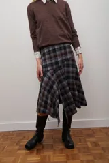 Falda midi de corte irregular con diseño a cuadros en tonos marrones, negros y beige. Presenta una silueta acampanada con caída fluida.