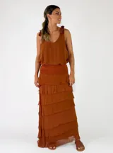 Top de viscosa color marrón tostado, sin mangas, con escote redondo y detalle de lazos para anudar en los hombros. Presenta un diseño de capas con volados en el ruedo.