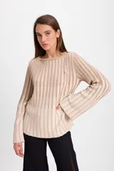 Sweater de punto con diseño de rayas verticales en dos colores, azul y crudo. Presenta cuello bote, mangas largas con terminación acampanada y un aplique decorativo en el pecho.