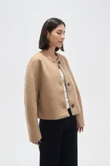 Tapado corto de paño color camel, con cuello redondo, cierre frontal de tres botones y mangas largas con diseño estructurado.