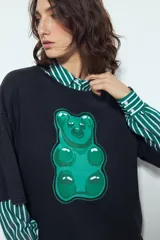 Remerón de manga corta con calce amplio y estética urbana, confeccionado con proceso de lavado que le otorga un efecto desgastado. Presenta una estampa gráfica frontal de un oso de goma en color verde.