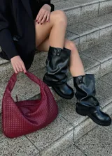 Botas de caña media color negro, con suela track y correas con hebilla plateada alrededor de la caña. El material es símil cuero.