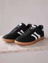 Championes urbanos Rusty, modelo Riadm, de color negro con detalles en blanco y suela de goma color caramelo. Presentan un diseño de estilo retro con cordones y logo de la marca en el lateral.