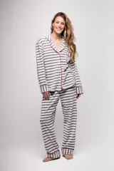 Pijama de tela tipo velvet a rayas horizontales grises y blancas, con vivos en color rojo. Incluye camisa de manga larga con botones frontales y bolsillo en el pecho, y pantalón recto con elástico en la cintura.