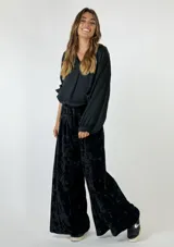 Pantalón palazzo de terciopelo color borgoña con textura arrugada y bolsillos laterales.