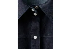 Camisa de denim azul oscuro, con cuello camisero, cierre frontal con botones y mangas largas ajustadas.