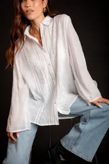 Camisa rosada con detalles de broderie en la parte delantera y mangas anchas.