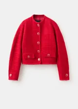 Chaqueta corta roja de tejido texturizado tipo tweed, con cuello redondo, bolsillos frontales con solapa, mangas largas y cierre de botonadura frontal con botones decorativos.