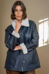 Campera reversible de cuero ovino con interior de piel sintética, diseño oversize, cierre frontal con broches y bolsillos laterales.