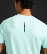 Remera deportiva de hombre con tecnología dry fit, cuello redondo y manga corta. Presenta un diseño liso en color beige con una pequeña etiqueta decorativa en el dobladillo.