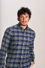 Camisa de manga larga confeccionada en tejido de franela con estampado de cuadros en tonos azul marino y verde. Presenta cuello abotonado, cierre frontal con botones y un bolsillo en el pecho con el logo bordado de la marca.