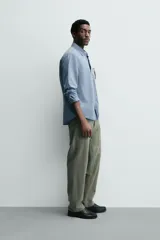 Camisa de corte relajado confeccionada en una mezcla de lyocell y algodón con efecto lavado. Presenta cuello solapa, manga larga con puños abotonados, bolsillo de plastrón en el pecho y cierre frontal con botones.
