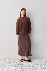 Falda midi color negro al bies, confeccionada en tela de textura suave y caída fluida, de diseño minimalista y silueta recta.