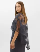 Vestido largo de corte sirena en color azul marino, confeccionado en tejido de punto con caída fluida. Presenta una capa integrada de tul fino sobre los hombros y espalda, decorada con bordados florales a tono y lentejuelas brillantes. Posee escote redondo y cierre invisible en la espalda.