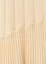 Vestido largo de punto fino color beige, con diseño evasé y plisado en la parte inferior. Presenta cuello halter y diseño sin mangas.