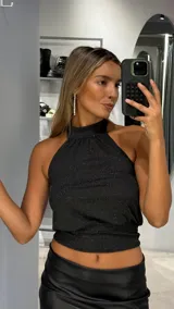 Top negro con cuello halter y acabado brillante, confeccionado en tejido elástico con ajuste al cuerpo.