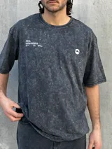 Remera gris con efecto lavado, corte oversize, manga corta y estampado pequeño en el frente.