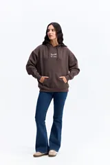 Canguro de algodón con capucha y bolsillo frontal, de diseño urbano y corte holgado. Presenta un parche rectangular en el pecho con detalles gráficos y el logo de la marca Mistral.