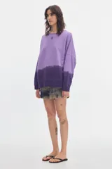 Buzo de felpa sin frisa color lila y morado con efecto degradé, cuello redondo, mangas largas y fit relajado. Incluye bordado pequeño en el centro del pecho.