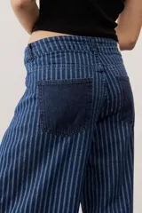 Jean de corte cargo y estilo holgado, con diseño de rayas verticales en tonos de azul. Presenta bolsillos laterales con solapa y detalles de tiras ajustables con hebillas en los tobillos.