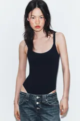 Body de cuello cuadrado con tirantes finos, confeccionado en tejido elástico con cierre inferior mediante botones a presión.