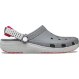 Zuecos Crocs modelo Classic Clog Turbo, color gris con suela blanca y detalles en rojo. Cuenta con perforaciones superiores para ventilación, correa trasera ajustable con sistema turbo y suela de goma para mayor tracción.