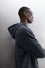 Sudadera de algodón con interior de rizo, corte relaxed fit, color gris oscuro. Cuenta con cuello con capucha y abertura frontal en V, manga larga y bajo con puños elásticos.
