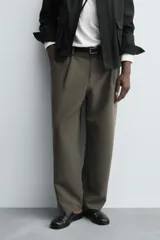 Pantalón de corte relajado en color verde militar, con diseño de pliegues frontales, bolsillos laterales y cierre de cremallera con botón.