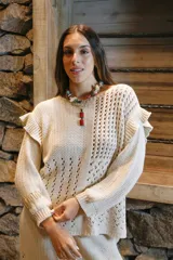 Sweater color crema tejido con hilo de algodón, cuello redondo, mangas largas abullonadas con volados en los hombros y calados en diferentes patrones.