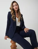 Blazer sastrero entallado color beige, con cuello de solapa, cierre frontal con un botón a tono y hombreras estructuradas. Presenta bolsillos laterales con solapa y forro interno.