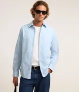 Camisa de corte regular, color celeste, con cuello inglés, mangas largas y cierre frontal con botones. Confeccionada en una mezcla de algodón y poliéster.