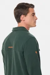 Camisa azul marino de poliéster con textura polar, corte recto, cuello camisero, cierre frontal con botones a presión, dos bolsillos de parche con solapa abotonada en el pecho y puños abotonados.