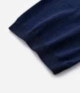 Remera polo azul marino de media malla con cuello y bajo a rayas blancas. Tiene cuello abotonado y mangas cortas.