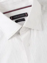 Camisa Tommy Hilfiger de corte regular, confeccionada en puro algodón regenerativo con diseño de raya diplomática y cuello con botones. Presenta el logo de la marca bordado en el pecho.