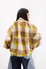 Campera bomber oversize de paño italiano con estampado en zigzag blanco y negro, cuello alto y cierre frontal con broches a presión. Tiene mangas murciélago.
