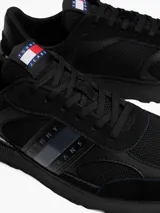 Zapatillas Tommy Jeans de corte bajo, color negro, con exterior de ante y detalles distintivos de la marca.