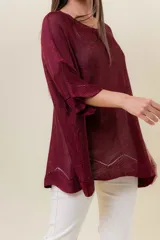 Buzo de tejido liviano con brillo sutil tipo lurex, color beige o dorado claro. Presenta un calce suelto (oversize) con mangas amplias y cuello redondo. El ruedo tiene un detalle de terminación festoneado con pequeños calados.