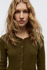 Saco de punto acanalado con cuello redondo, cierre frontal con botones metálicos y diseño entallado con peplum en la cintura.