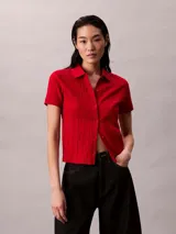 Chomba roja de Calvin Klein confeccionada en algodón con textura jacquard y estampado integral del logo. Cuenta con cuello polo, manga corta, cierre frontal con botones y detalles acanalados en los puños y el dobladillo.