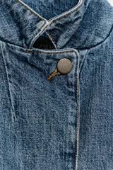 Blazer cropped de denim azul con cuello subido, manga corta y bolsillo de vivo en el pecho. Cierre frontal con botón.