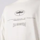 Remera oversize de algodón color crudo, con hombro caído, cuerpo amplio y estampa gráfica frontal en color negro con diseño de libélula y texto.