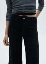 Jeans estilo culotte de tiro alto, color negro, con cierre de cremallera y botón, trabillas para cinturón, bolsillos traseros y bajo deshilachado.