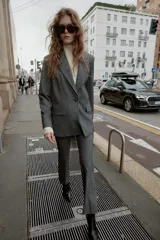 Blazer recta gris con hombreras, cuello solapa, manga larga, bolsillos delanteros con solapa y cierre frontal con un botón.