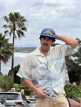 Gorra de béisbol azul marino con visera curva y bordado frontal en amarillo que dice "LOVE & PEACE" y debajo "PP:ONE".