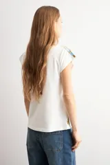 Remera blanca de manga corta, con escote en V y detalles de estampa paisley en los hombros y en el borde inferior.