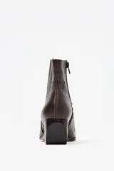 Bota corta estilo texano de cuero color chocolate con textura de cocodrilo y detalles de costuras decorativas. Cuenta con taco cuadrado y punta fina.